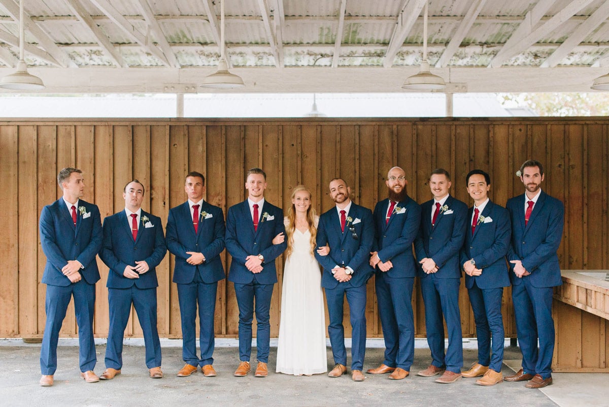 Groomsmen posed with Tiffany wearing blue suits and red Ties.com neckties