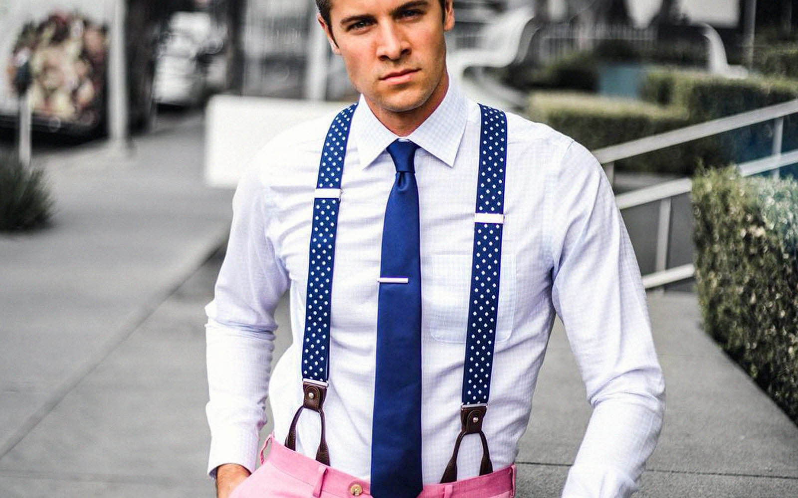 Male model wearing white button up with blue tie and blue polka dot suspenders