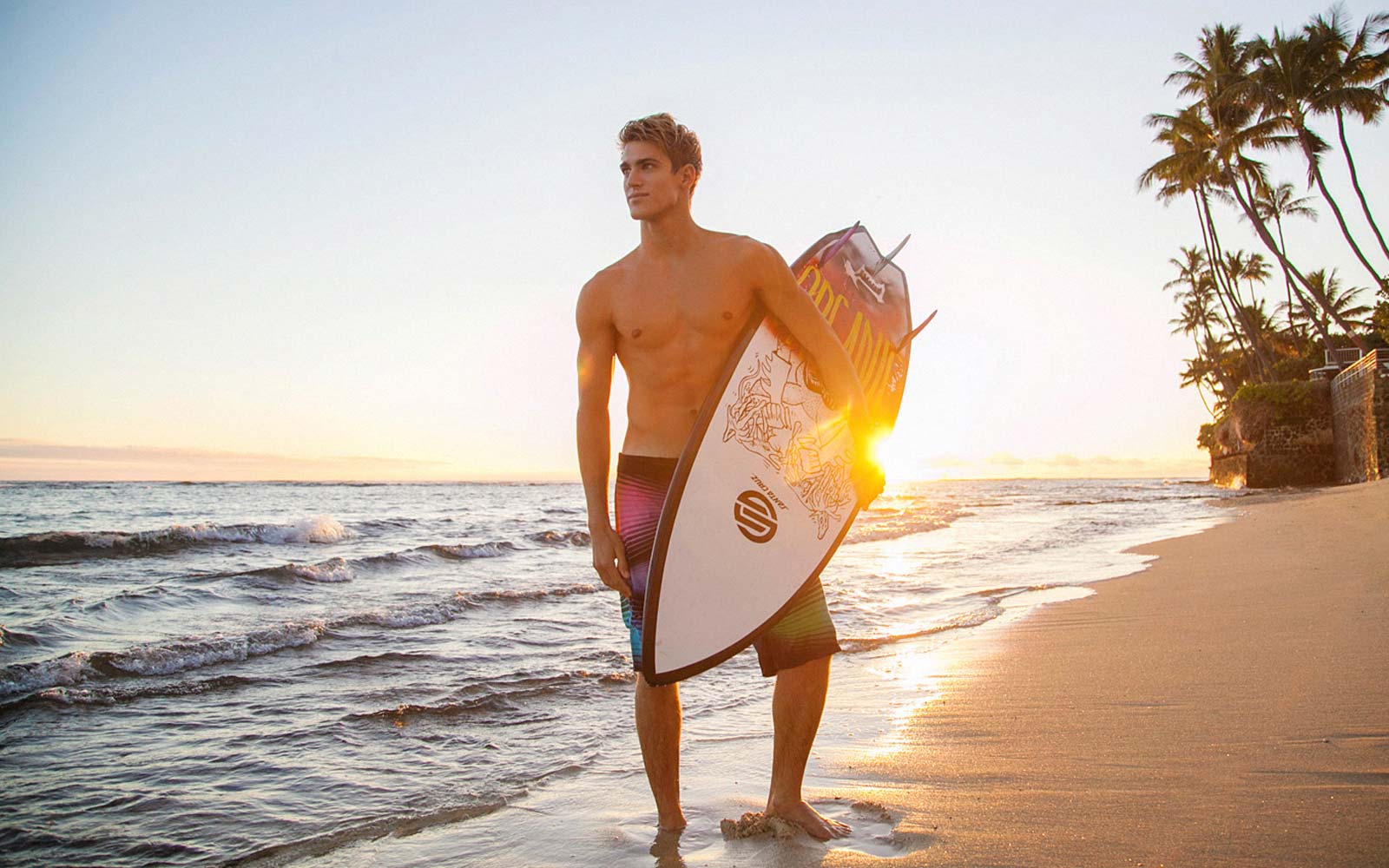 Man on beach holding surfboard