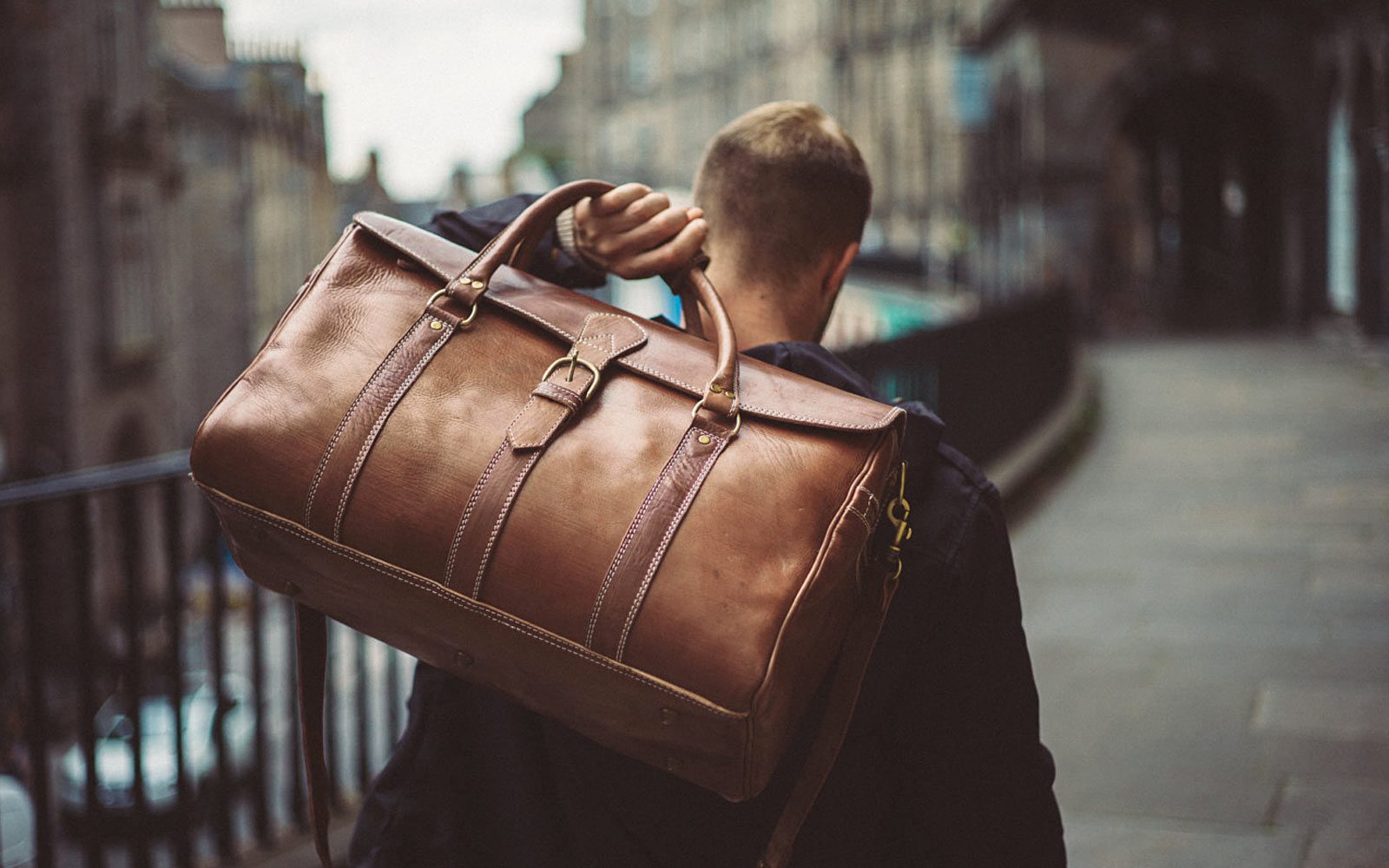 man carrying leather duffle bag