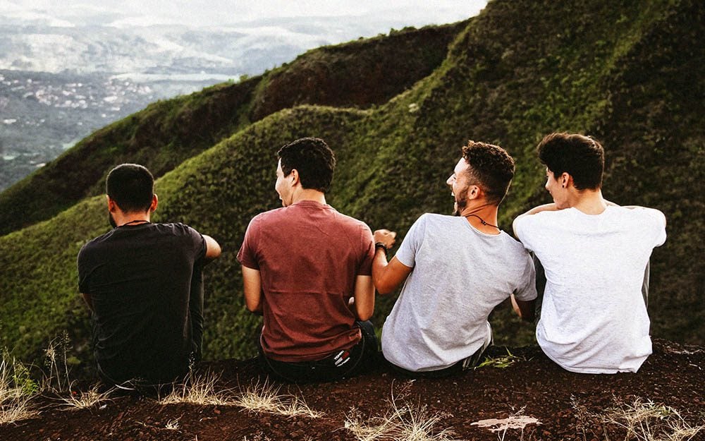 four men sitting overlooking a view