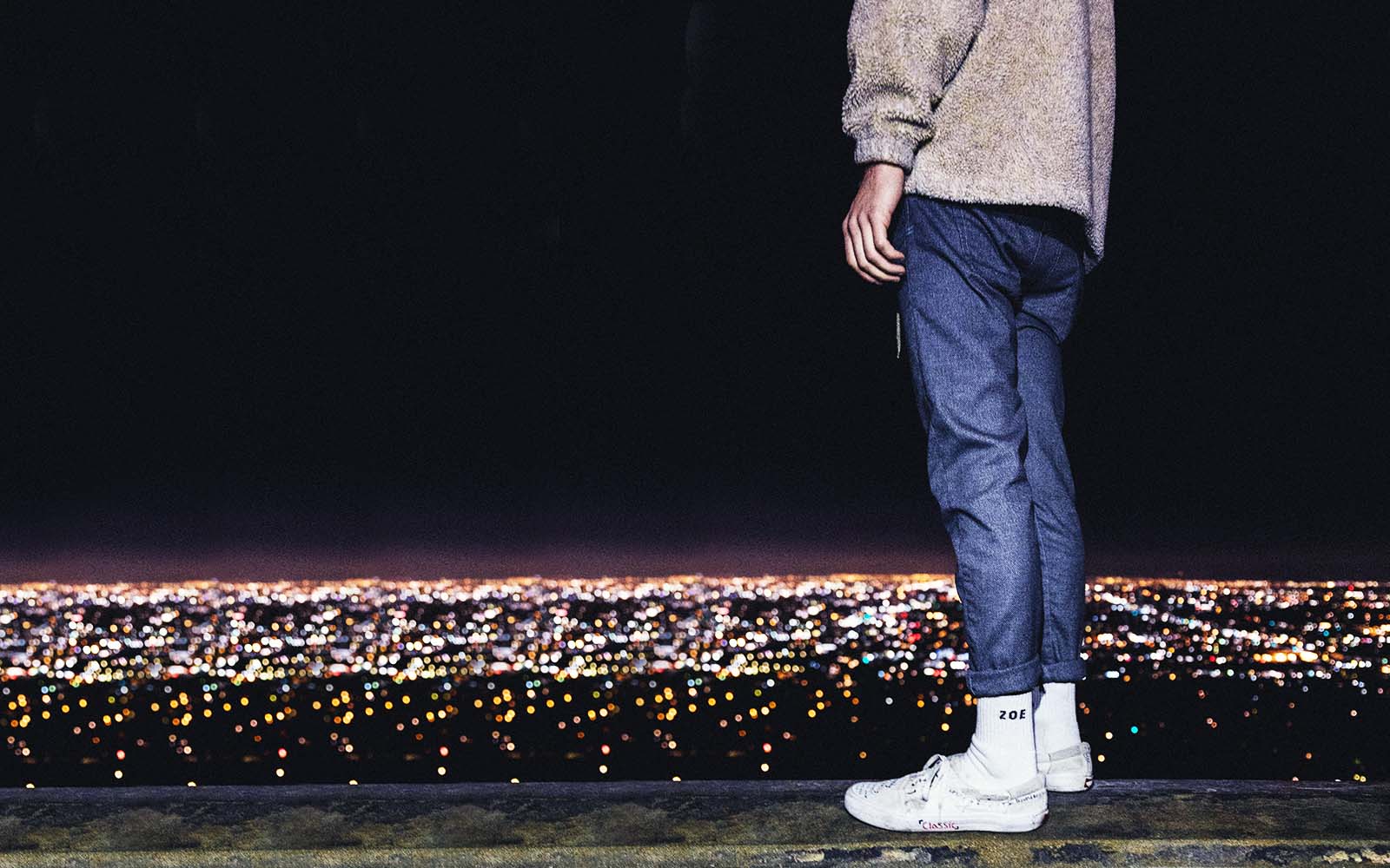 man wearing jeans looking out at city view