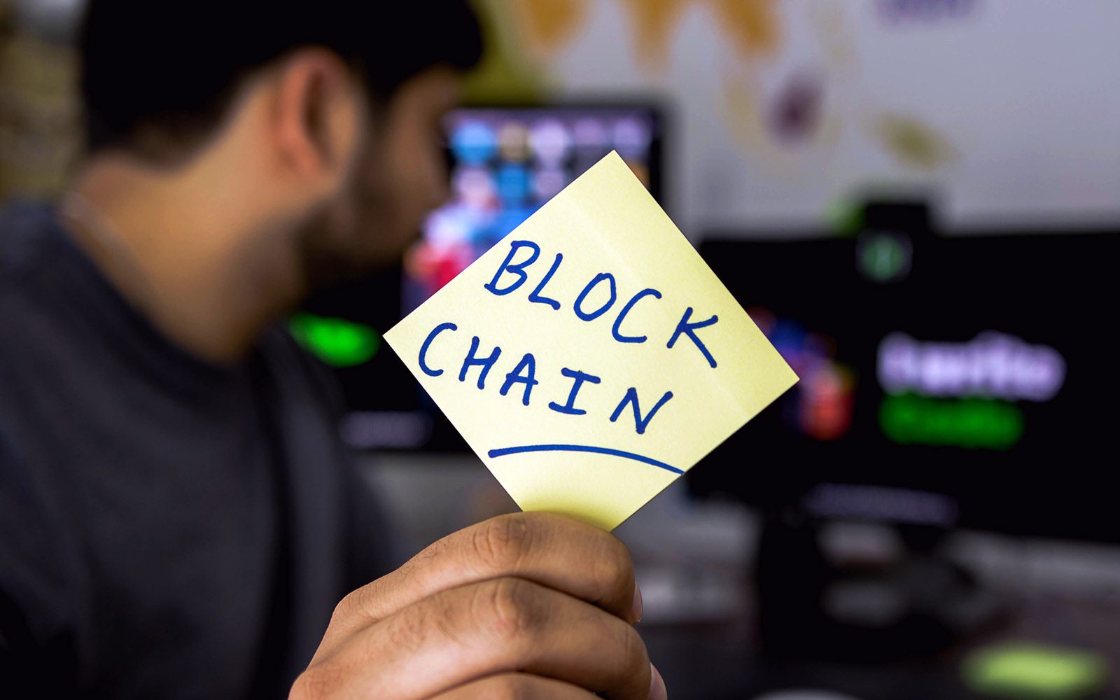 man holding post it note with blockchain inscribed